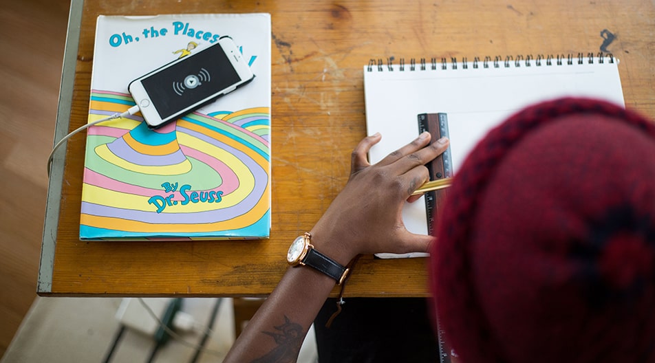 Student at desk with ruler and phone