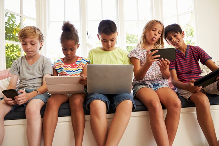 Children sitting and playing with their gadgets 