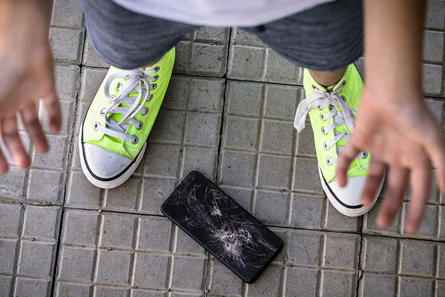 Smashed phone on floor with person standing over it